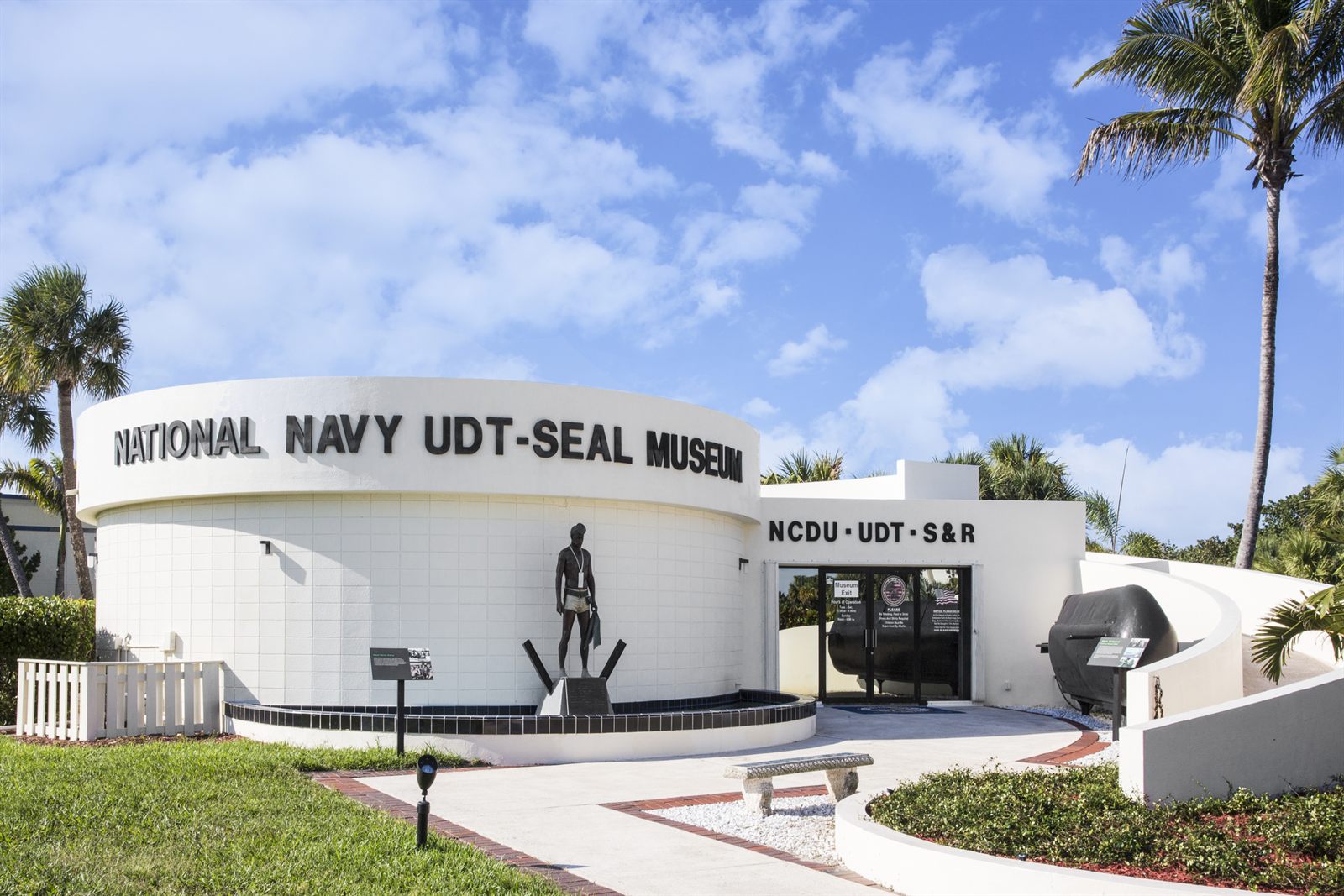 The round white National Navy UDT-SEAL Museum building with a statue of a frogman outside